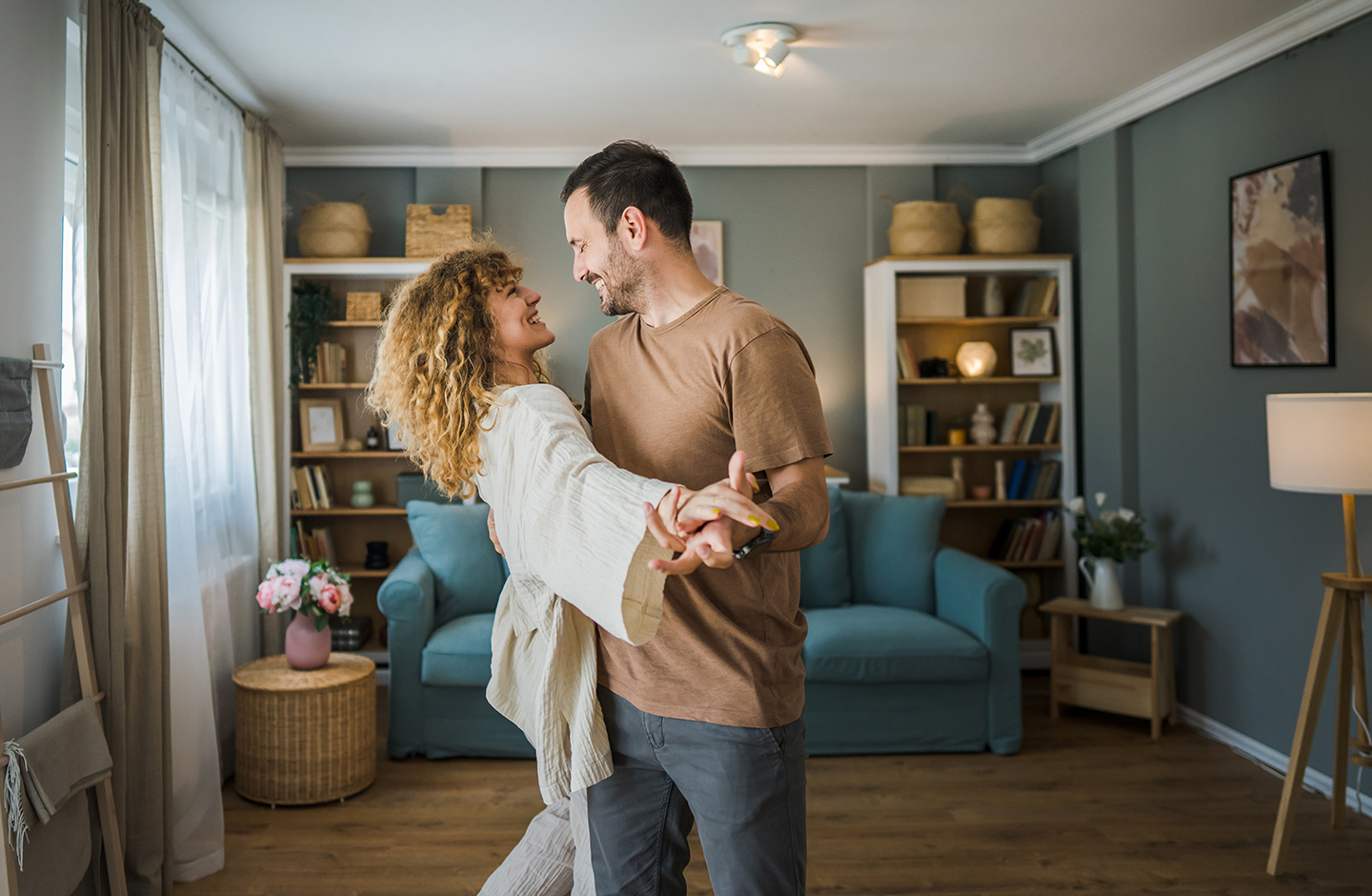 Ein junges Pärchen tanzt in ihrem neuen Wohnzimmer